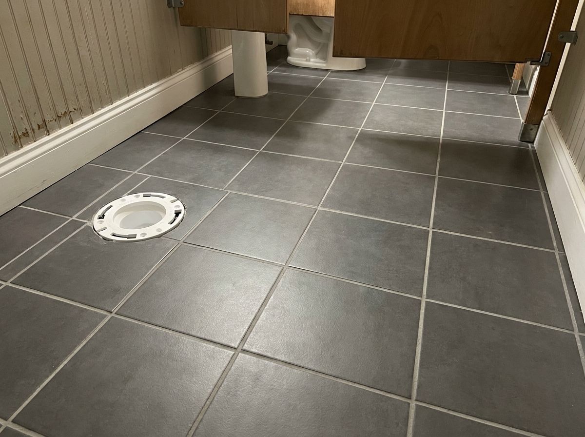Commercial restroom floor after tile replacement with clean grout