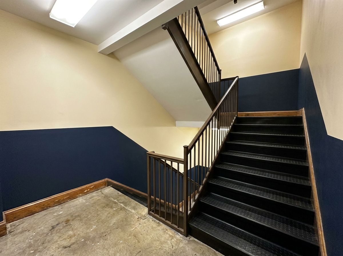 Commercial stairwell repaint with two-tone walls and repainted railing