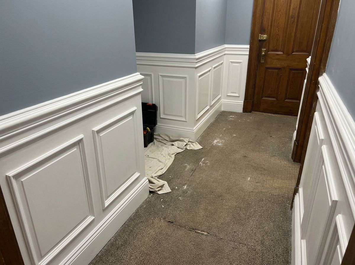 New wainscoting and chair rail along a commercial hallway wall