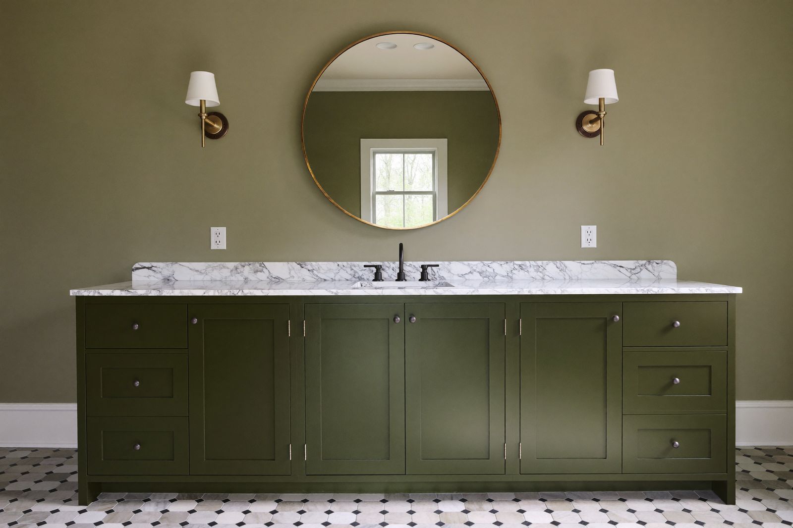 Green painted double vanity with marble top, round brass mirror, and hex tile floor