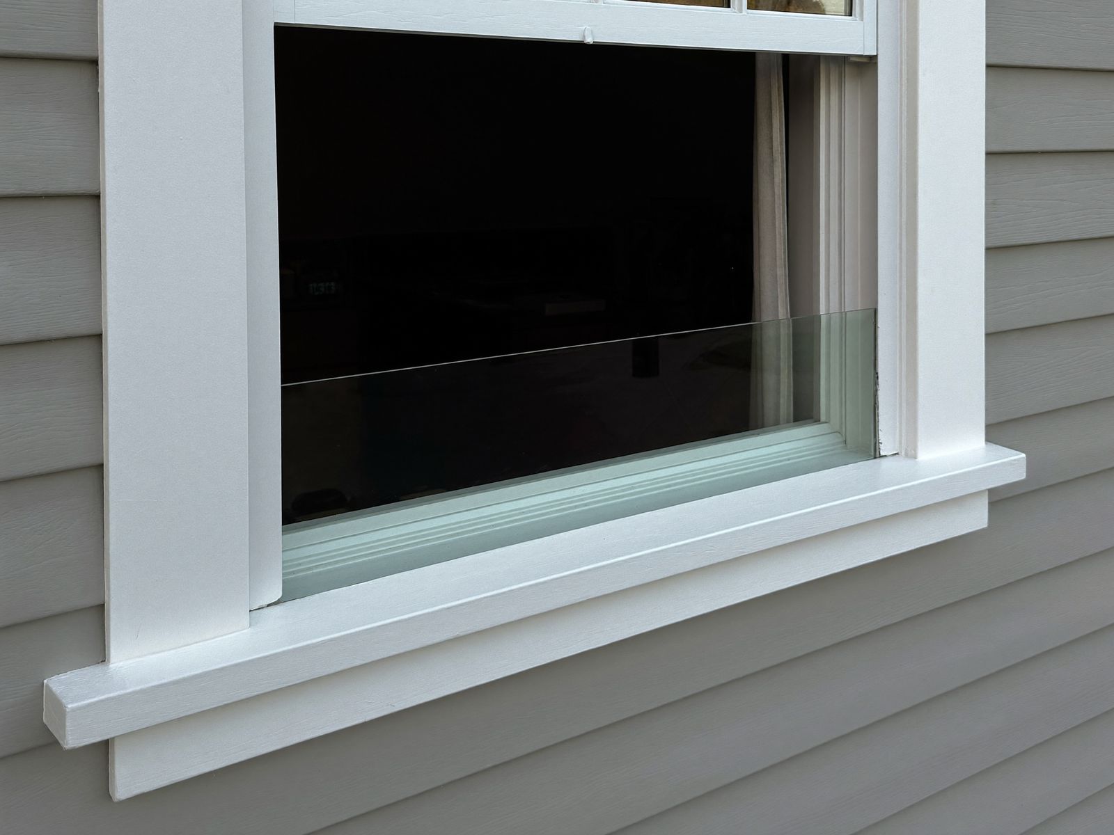 Freshly primed replacement window sill against clapboard siding