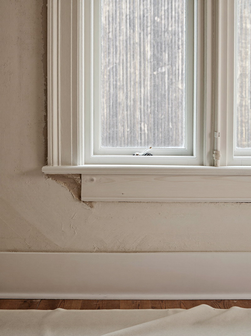 New primed window casing and stool installed against an older plaster wall with tight mitered joints