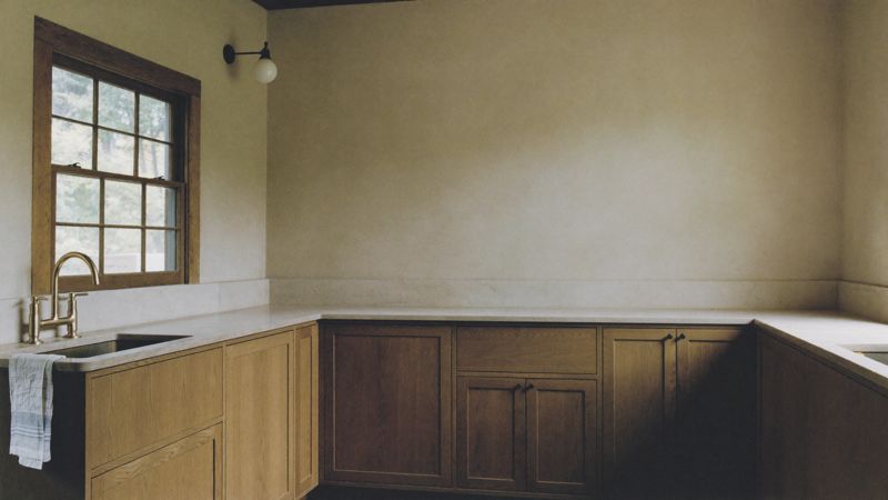 Oak kitchen cabinetry with soapstone counter and brass bridge faucet