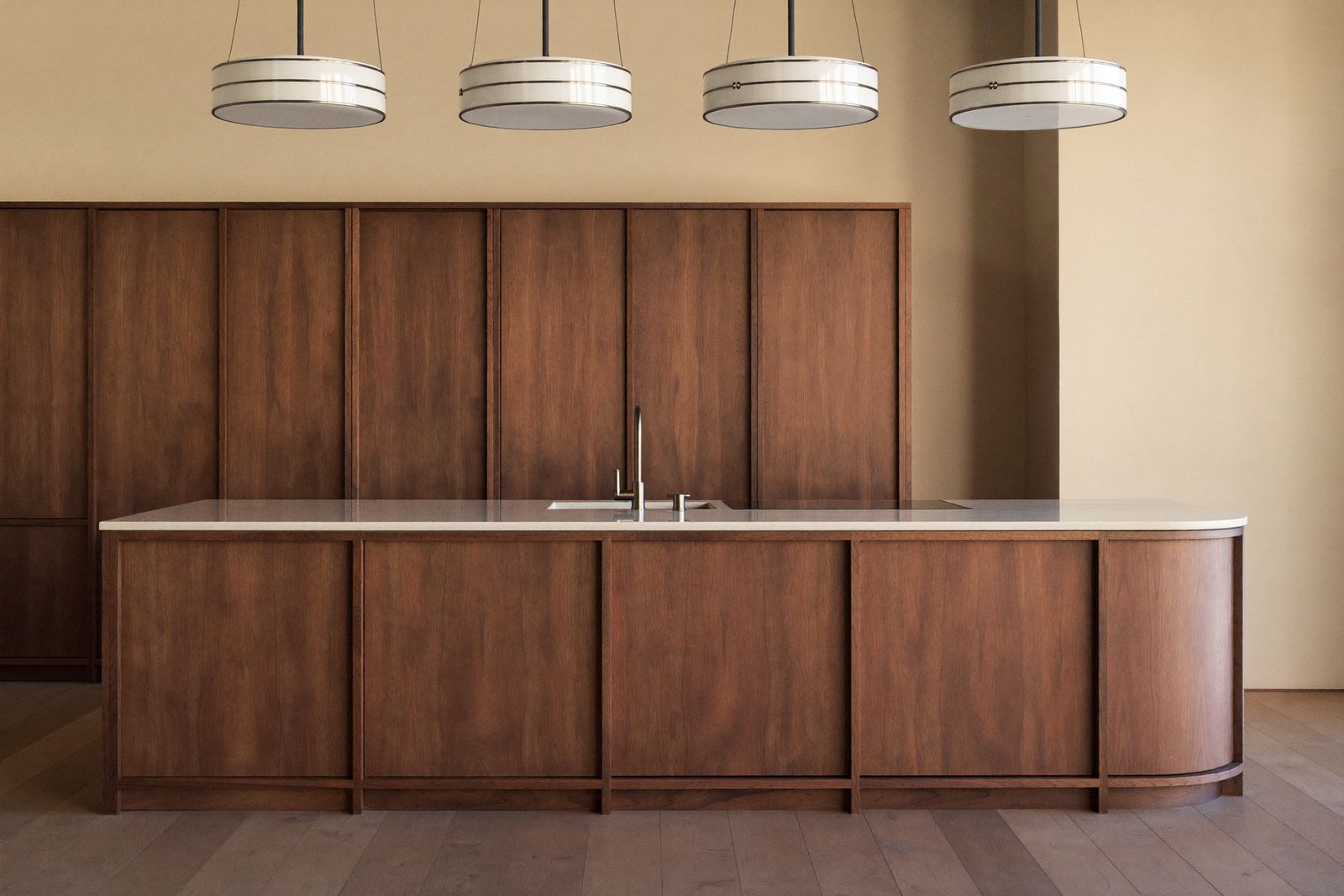 Walnut kitchen island with stone top and linen drum pendants