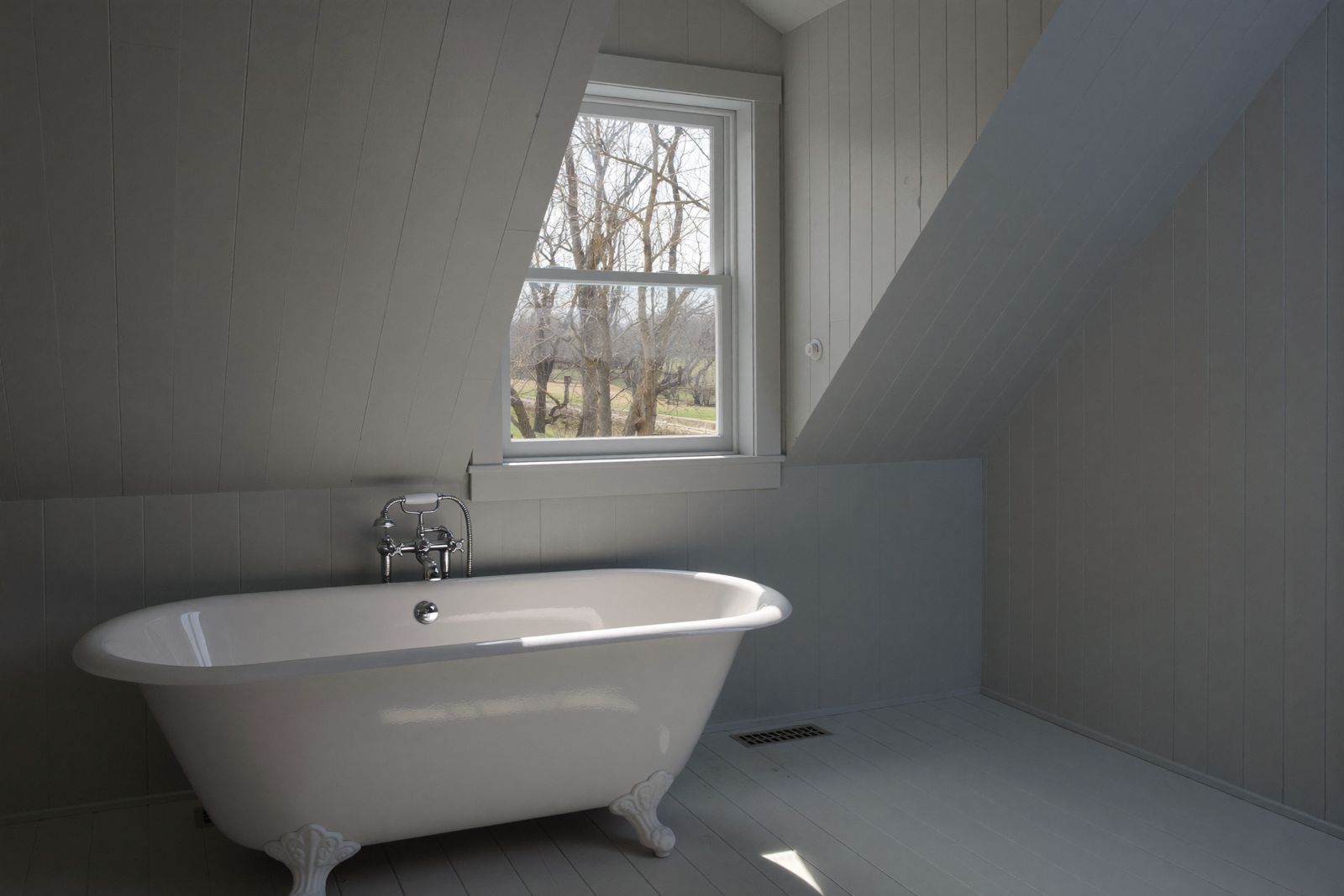 Freestanding tub under a dormer window in a Cape-style bathroom