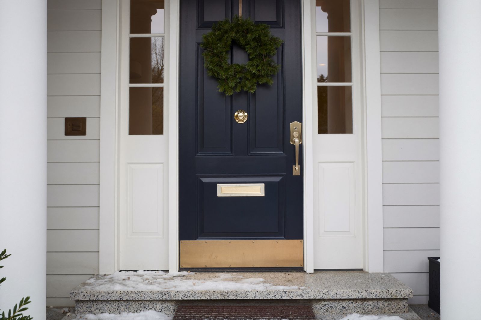 Navy painted front door on a Cape-style entry in winter