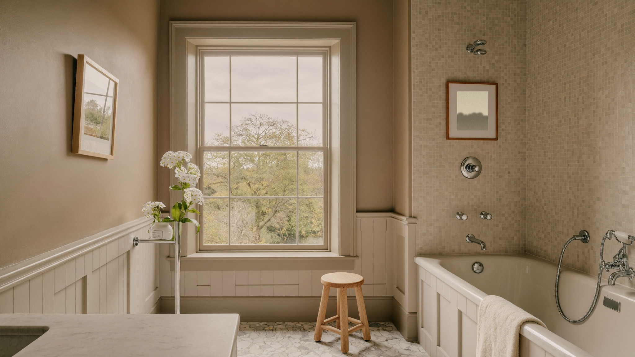 Editorial photograph of a serene renovated bathroom in an older Brookline Massachusetts home: tall double-hung window with deep period casing