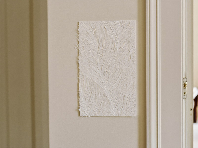 Feathered plaster repair beside deep original door trim in an older hallway, primed and sanded ready for paint