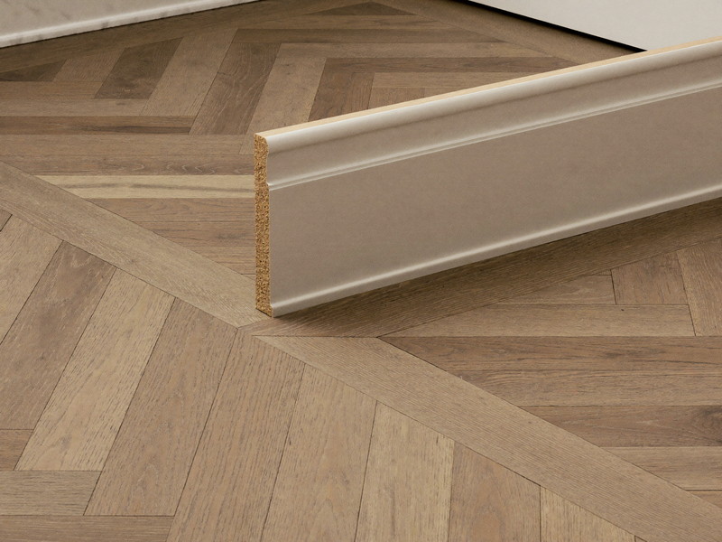 Repaired baseboard and quarter-round scribed tight to an original oak floor in an older home, primed and painted to match the deep period profile