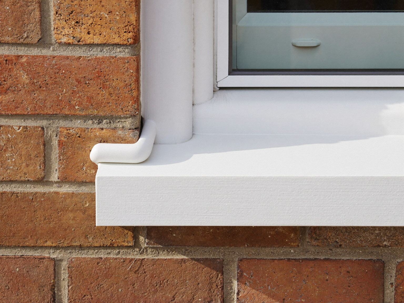 Neat weatherproof sealant bead where aged brick meets a white painted window sill, freshly tooled on an older Brookline home