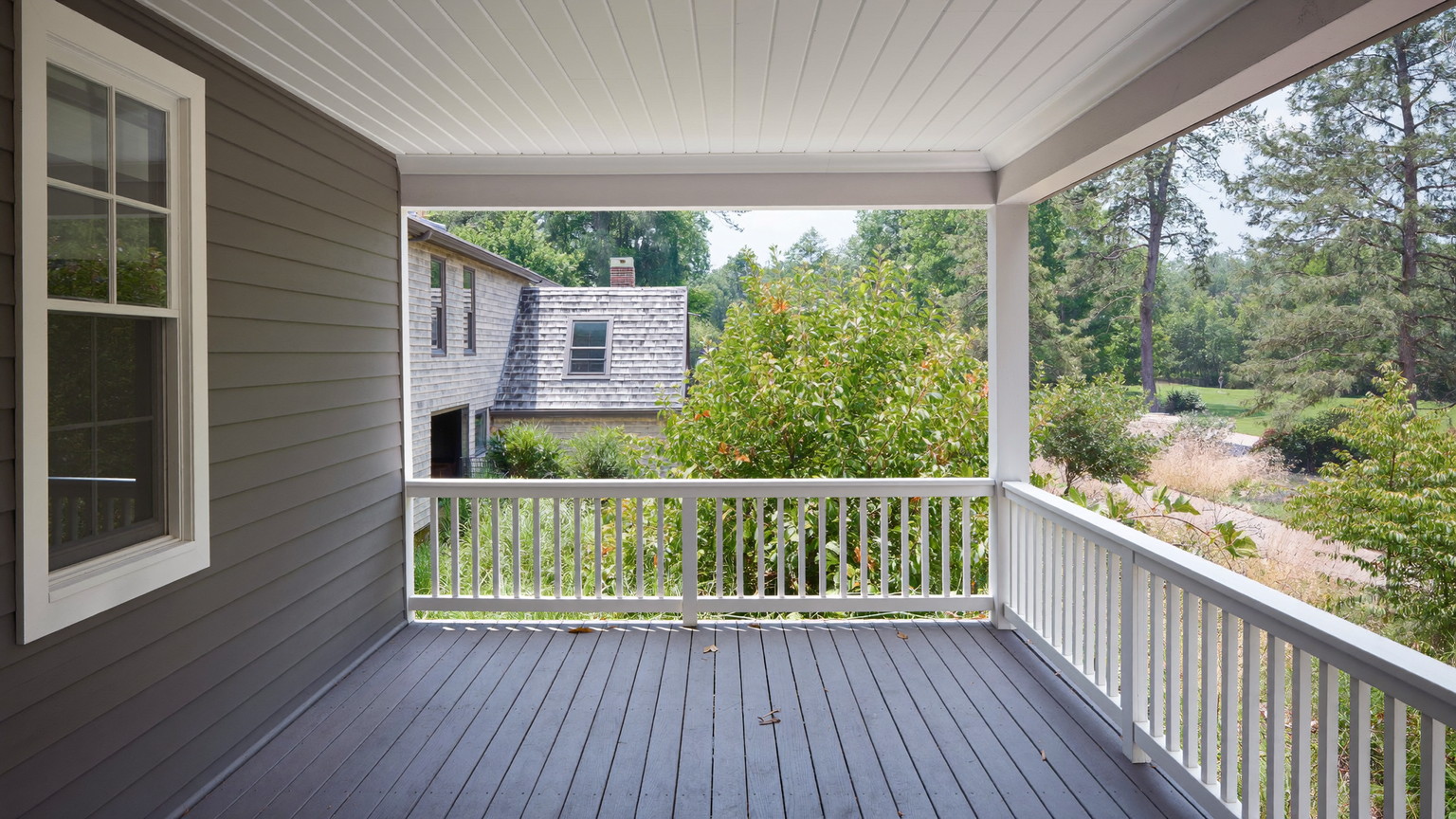 Editorial photograph of a rebuilt second-floor rear porch on an older Cambridge Massachusetts home: painted gray fir decking, crisp white square balusters and
