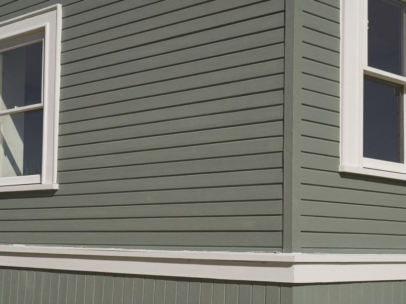 Detail of a freshly repainted clapboard corner on an older wooden city home: soft gray-green clapboards, crisp bright white corner boards and window casings