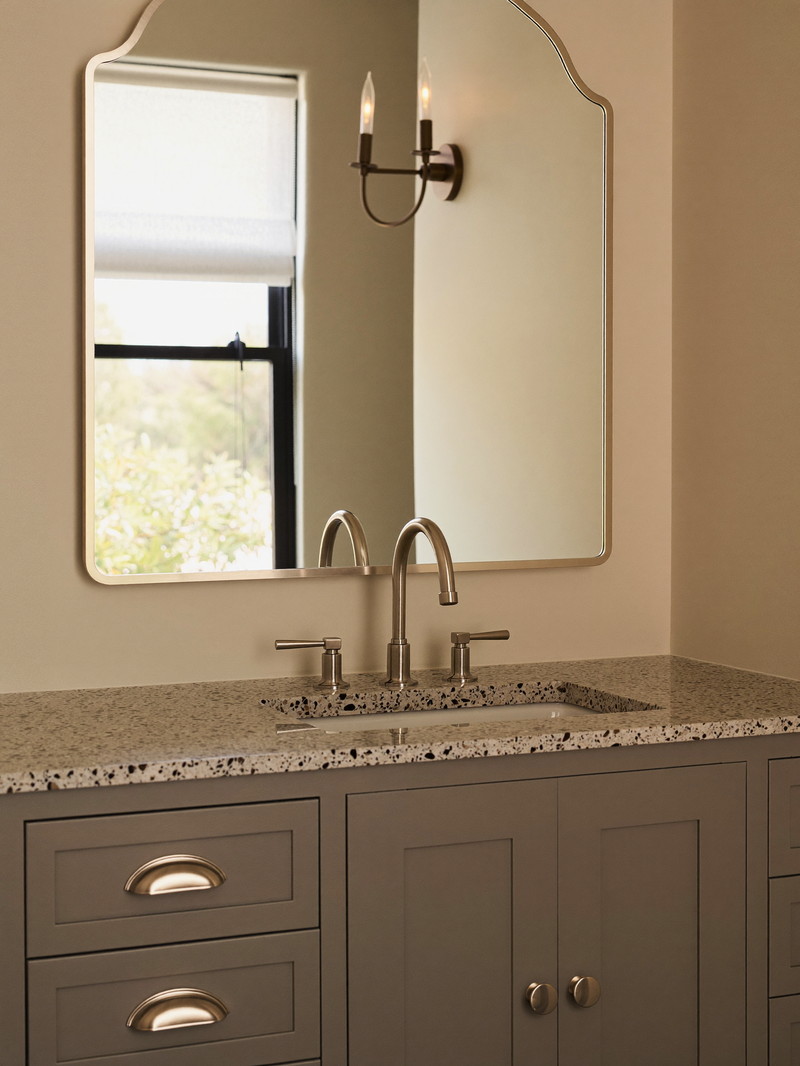 A warm taupe painted bathroom vanity with a honed speckled granite top and satin nickel faucet with smooth lever handles