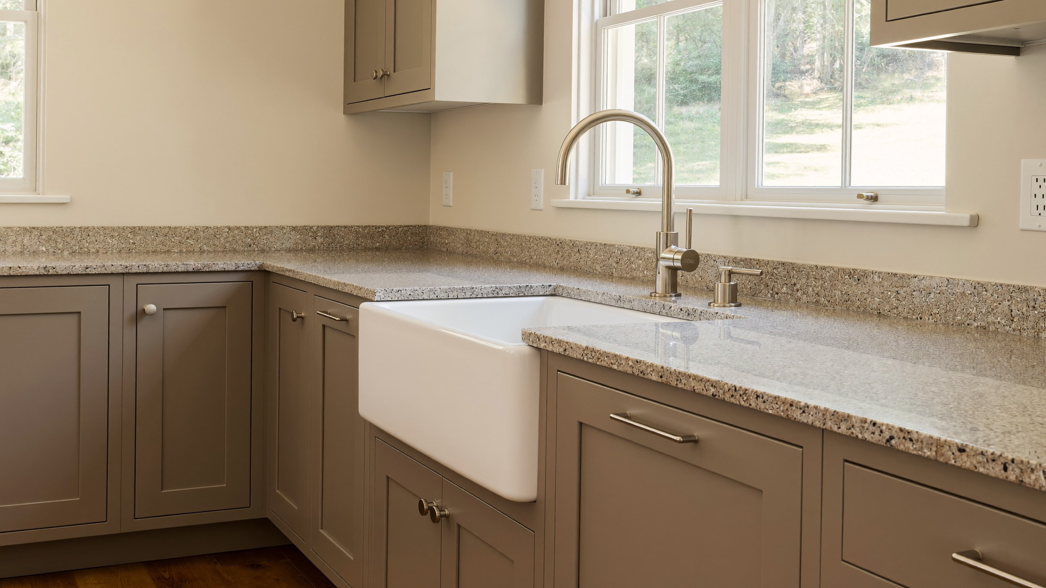 A renovated family kitchen in an established Framingham Massachusetts colonial, photographed for a design journal: warm taupe shaker cabinetry