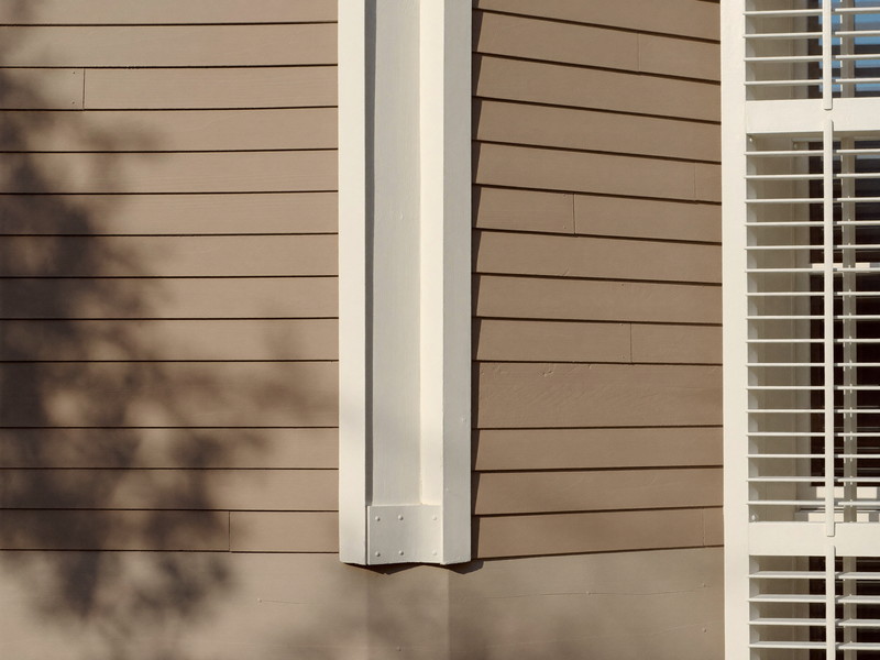 Detail of freshly repainted warm taupe clapboard siding on an established Framingham colonial: narrow horizontal clapboards, a crisp white corner board