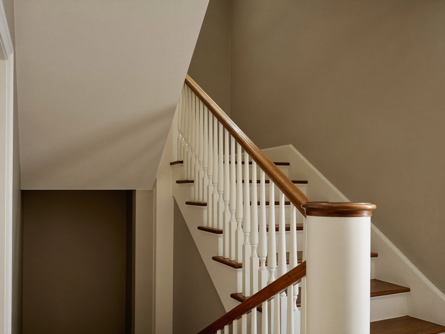 A finished repainted stair hall in an established Framingham colonial: warm greige walls over smooth restored plaster