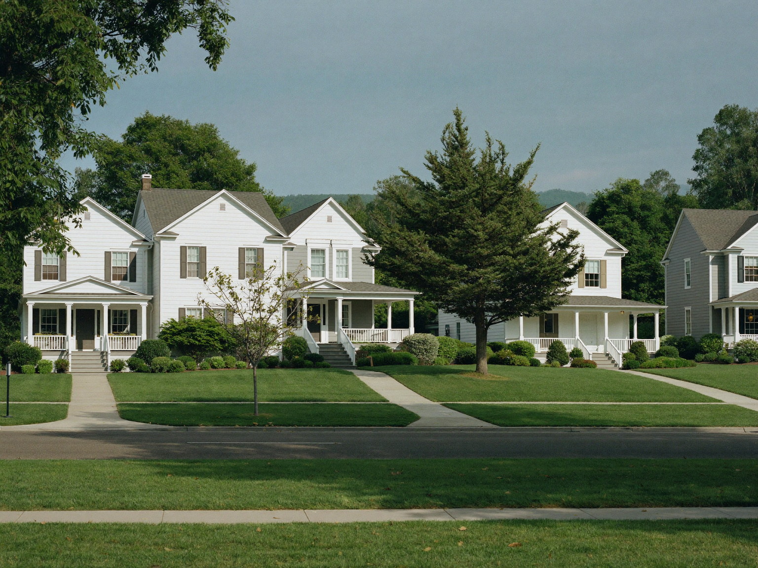 A quiet Framingham Massachusetts street of comfortable freshly painted family homes: two-story white and taupe colonials and capes with white trim and front porches