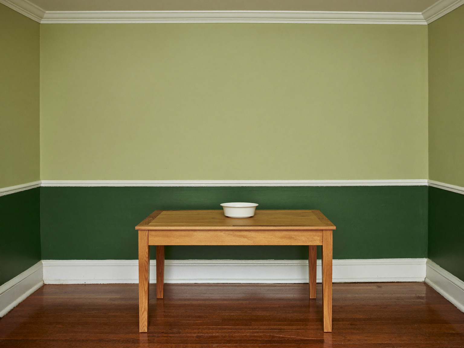 A repainted dining room in an established Framingham colonial: warm greige walls above a chair rail, deep forest-green below, glossy white trim and crown molding
