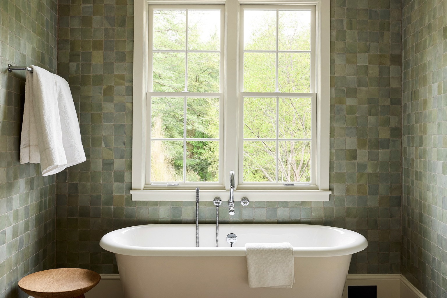 Green painted double vanity with marble top, round brass mirror, and hex tile floor