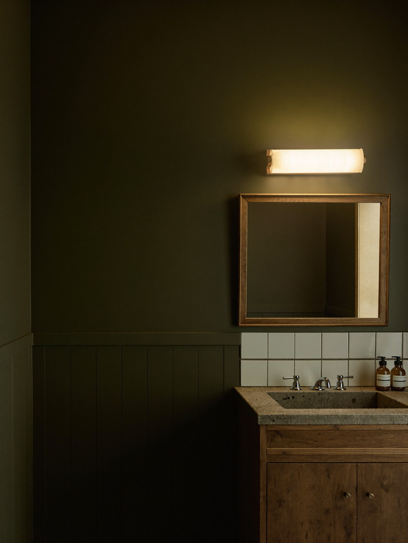 Narrow bathroom with olive-green beadboard, walnut vanity, and penny tile floor