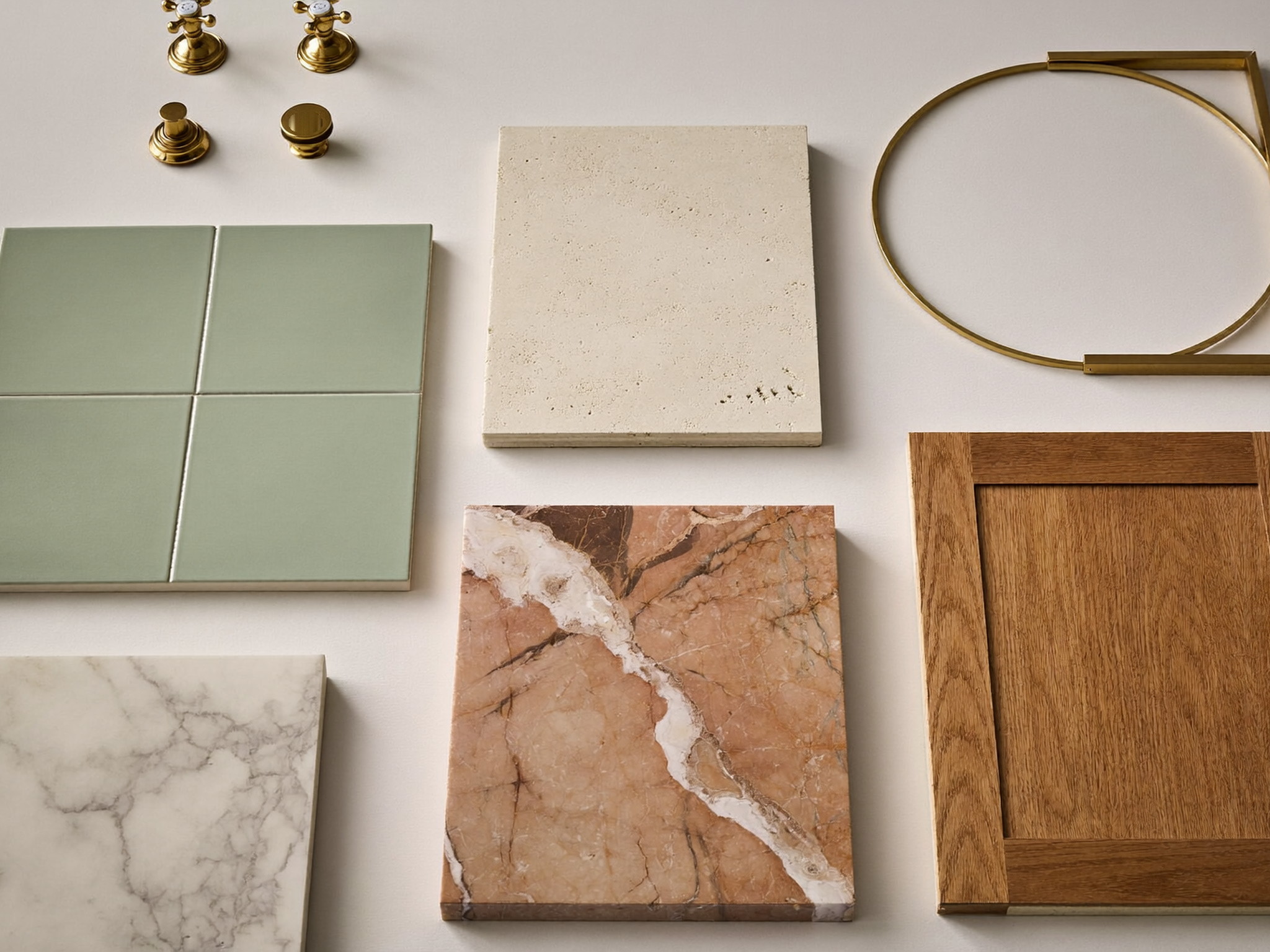 Bathroom material samples — zellige tile, marble, rift oak, and brass — arranged on linen beside a pencil sketch