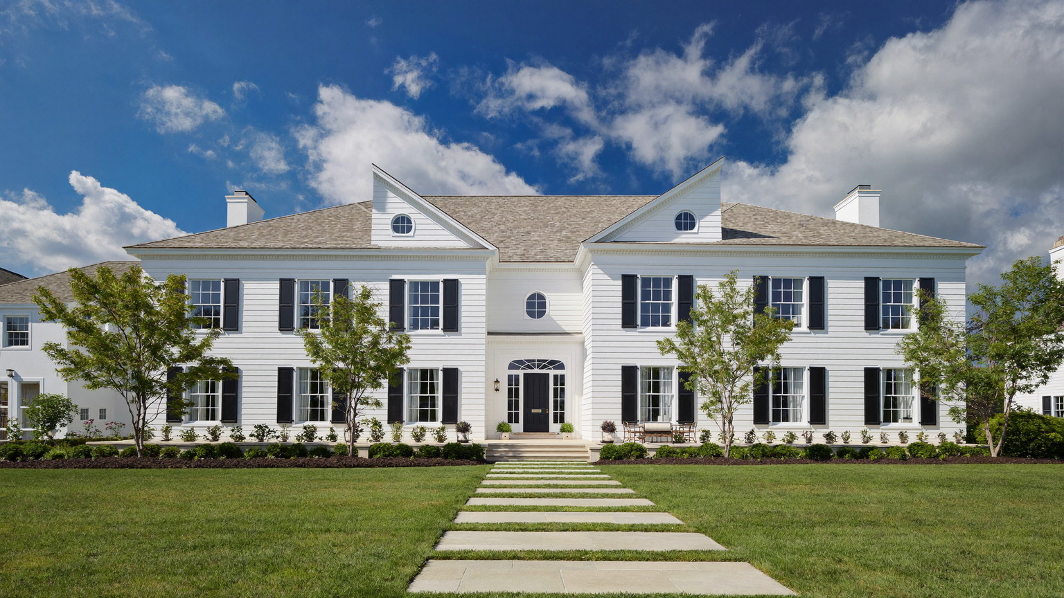 Beautifully maintained white New England colonial with black shutters and crisp trim in summer light
