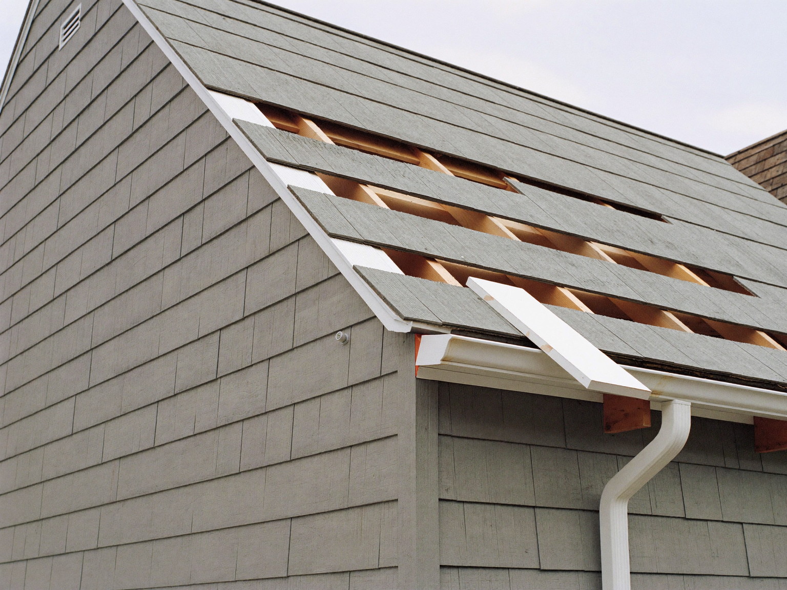 Exterior weather repair in progress — siding opened, new sheathing in place; illustrative imagery