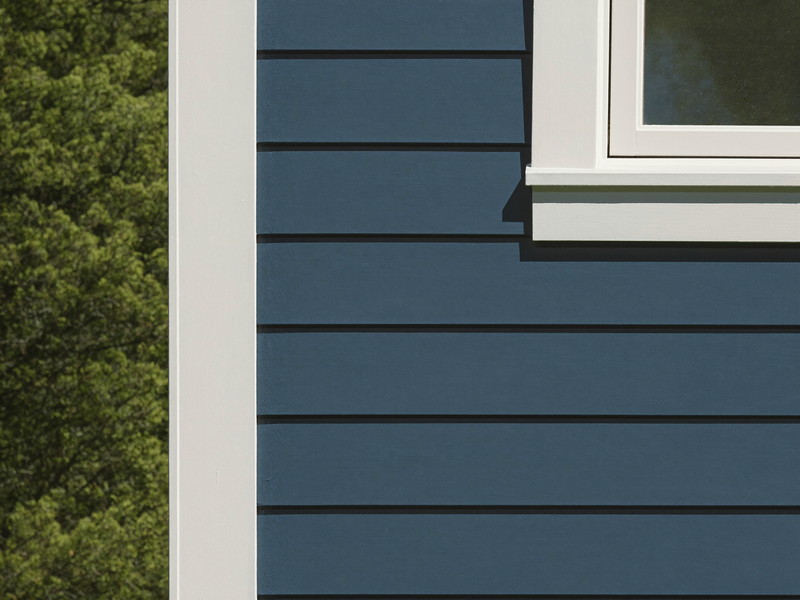 Sage green clapboard siding meeting a bright white corner board and window casing with sharp paint edges
