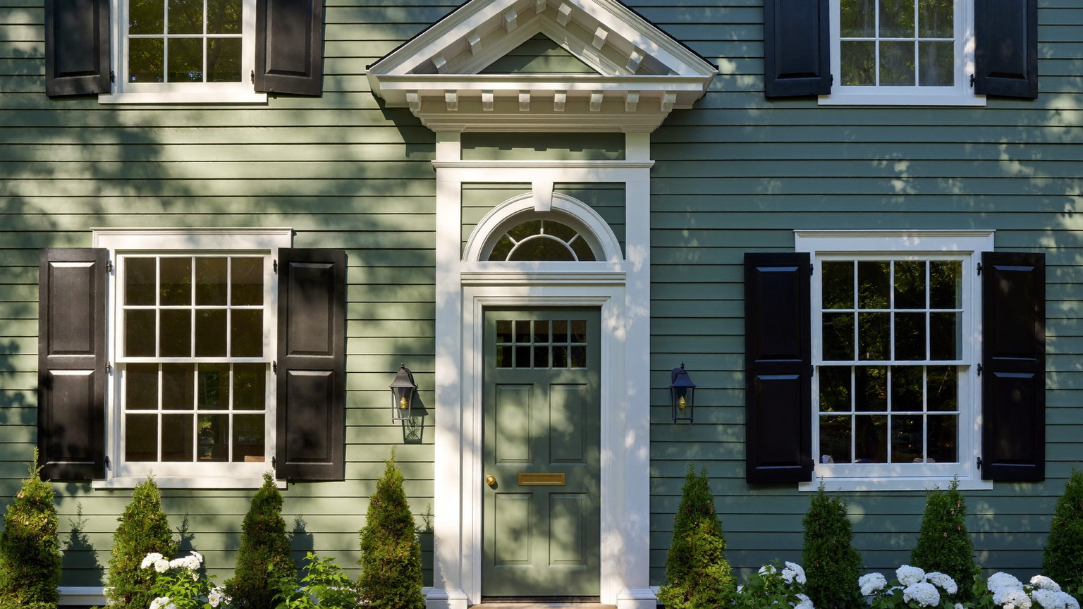 Sage-green New England colonial with crisp white trim and black shutters — illustrative painting imagery