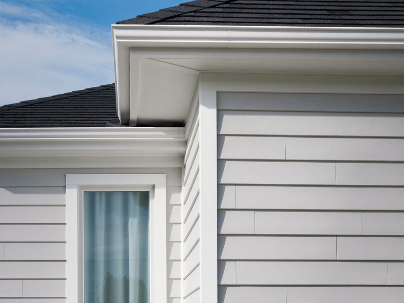 Freshly repainted white clapboard siding meeting a bright white corner board and window casing on an established New England home, dark asphalt shingle roof
