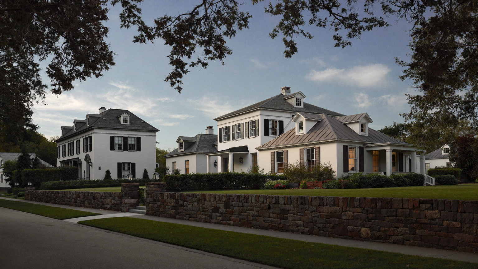 A quiet Lexington Massachusetts residential road in early evening: dignified established detached colonials and antique capes set apart on deep green lawns behind low fie