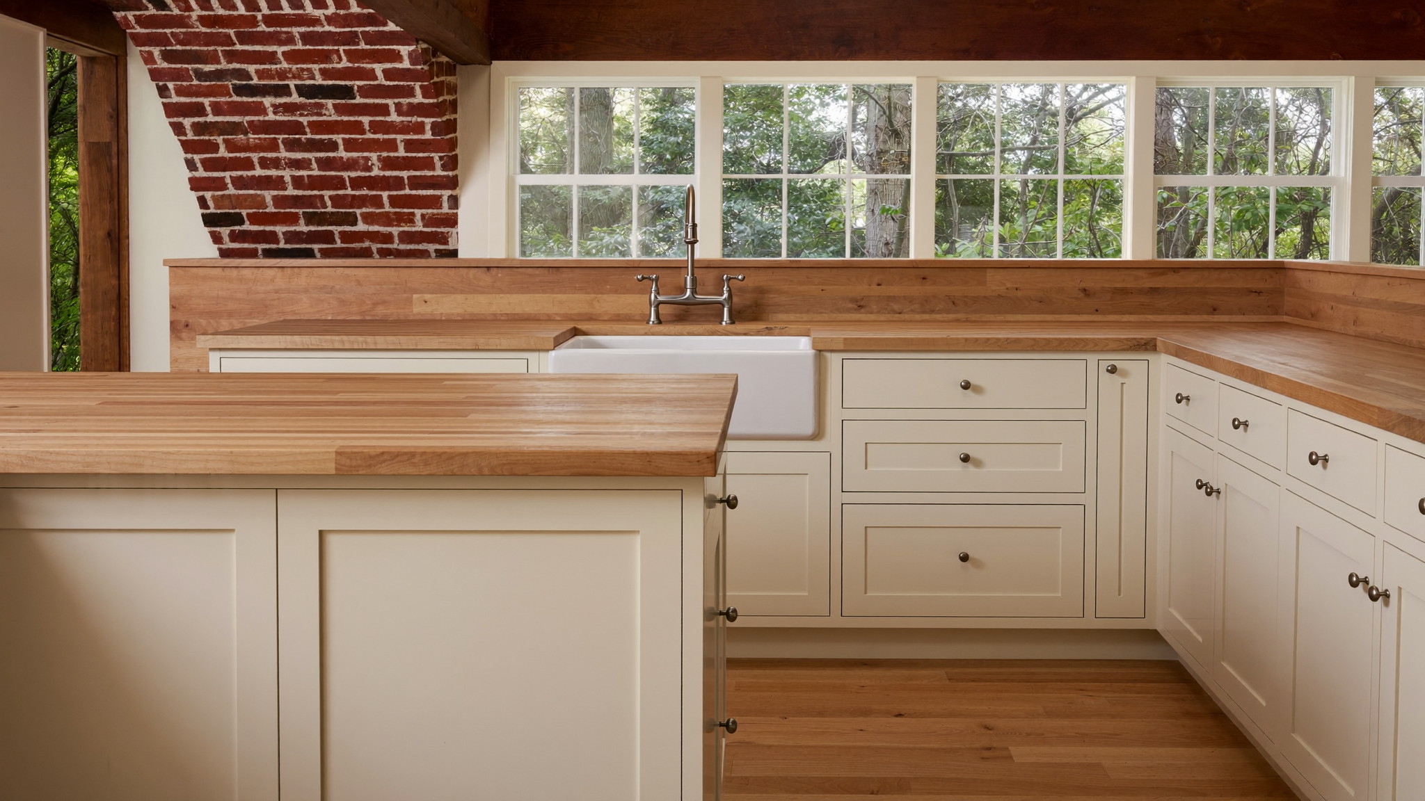 A renovated family kitchen in a historic Lexington Massachusetts colonial, photographed for a design journal: ivory shaker cabinetry, warm maple butcher-block counters