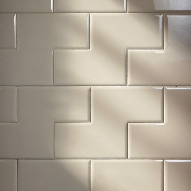 Glossy white beveled subway tile with soft warm-gray grout lines, gentle glaze variation catching raking light across a flat shower wall