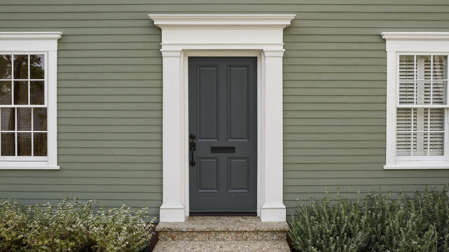 A freshly painted New England colonial entry: muted sage-green clapboard siding, crisp white trim and casing, deep charcoal front door in satin enamel