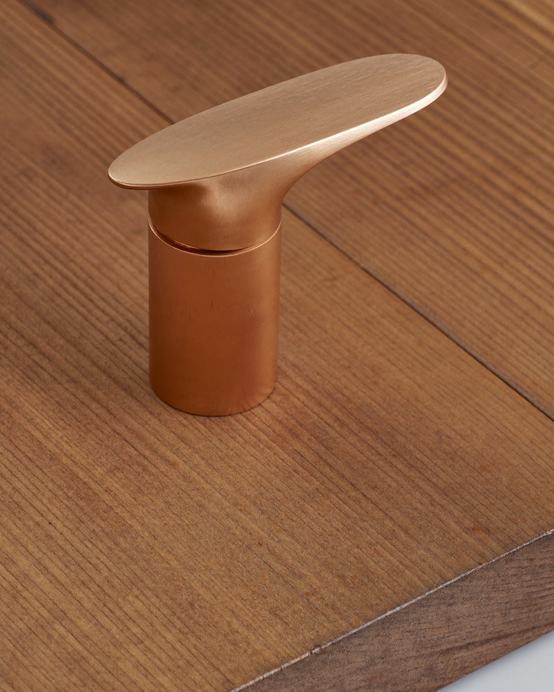 A brushed copper bathroom faucet with a gentle arched spout and a single smooth lever handle, completely plain unmarked metal, mounted on butcher-block