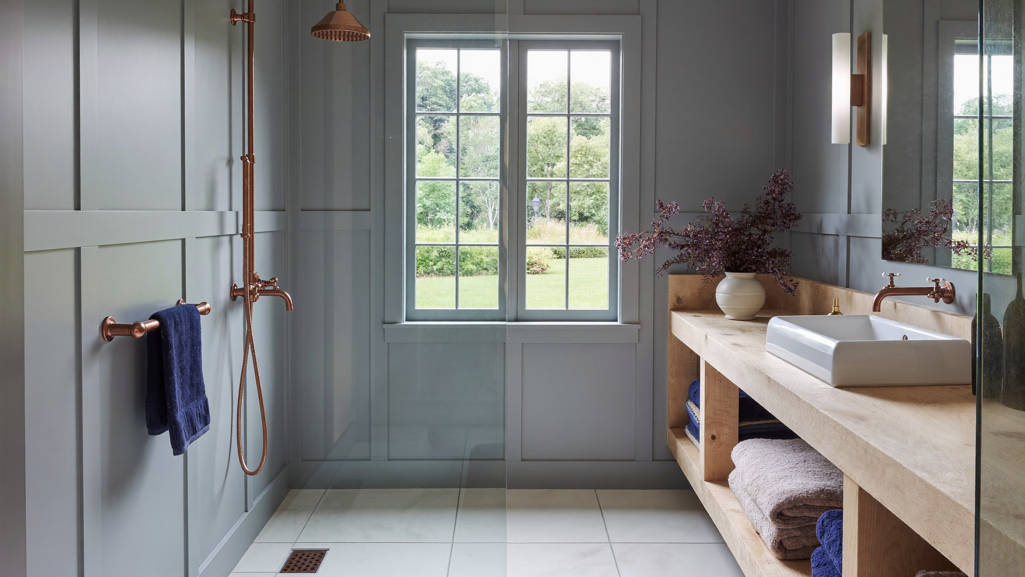 A serene renovated bathroom in a comfortable Medway Massachusetts colonial, photographed for a design journal: soft blue-gray painted paneling, brushed