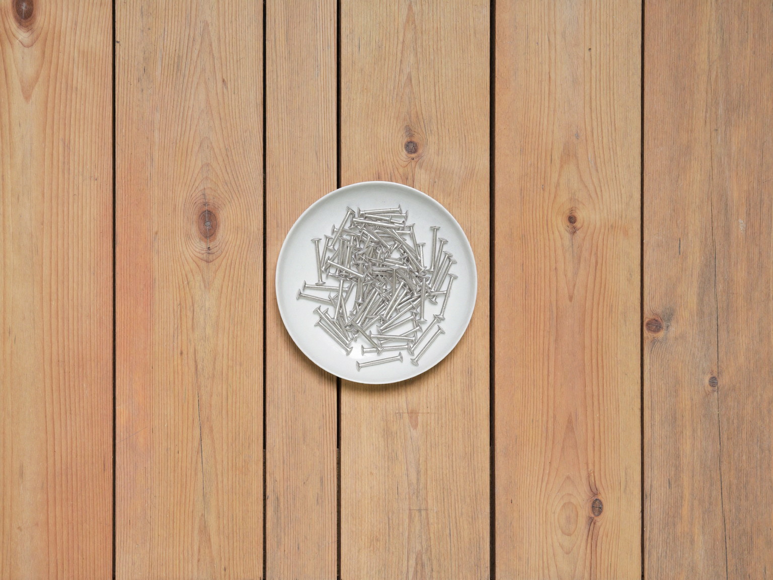 Overhead view of fresh fir porch flooring boards with visible natural wood grain laid tongue-and-groove side by side, one plain white ceramic dish of