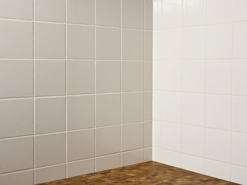 Freshly regrouted warm white square ceramic tile in a suburban kitchen backsplash corner: clean bright grout lines, every tile flat and straight, edge of