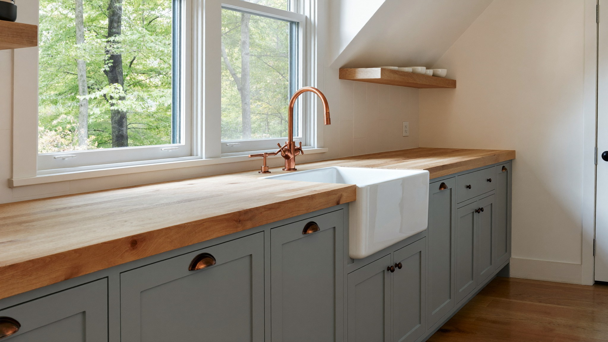 A renovated family kitchen in a comfortable Medway Massachusetts colonial, photographed for a design journal: soft blue-gray shaker cabinetry, thick