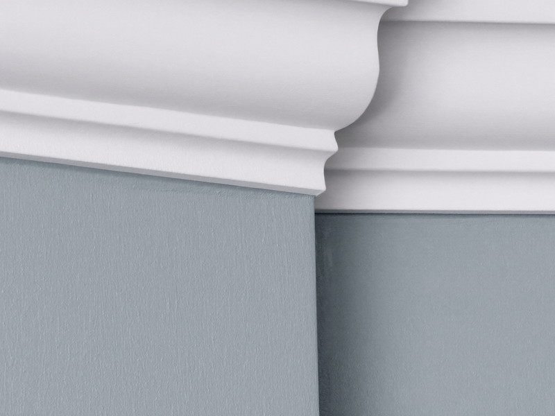 A razor-sharp paint line where a soft blue-gray wall meets bright white crown molding, the edge perfectly straight and clean, smooth fresh paint on both