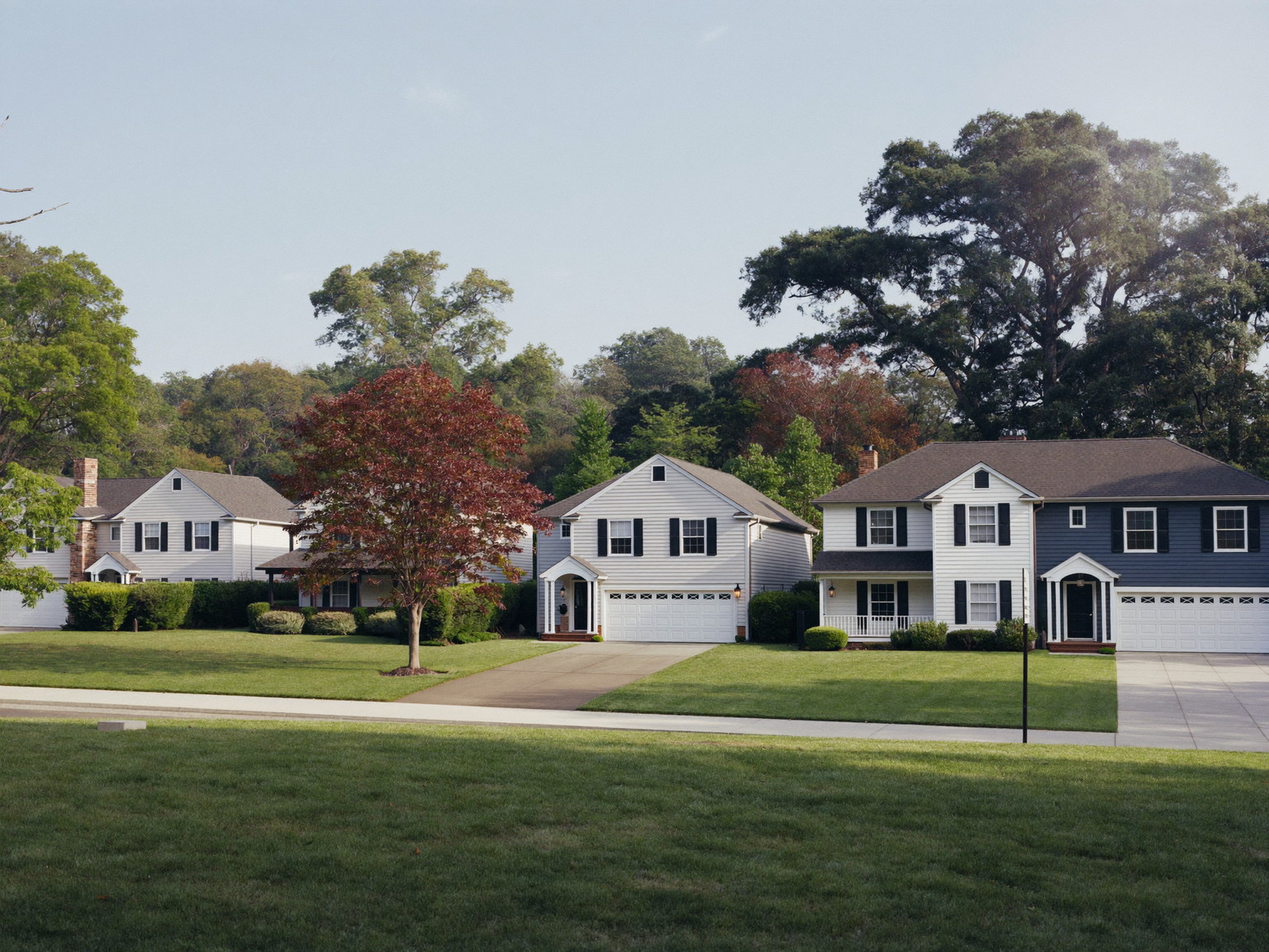 A quiet Medway Massachusetts street of comfortable freshly painted family homes: two-story white and blue-gray colonials and capes with white trim and