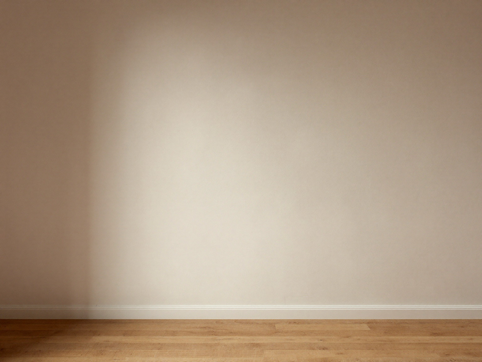 New skim-coat plaster drying under soft raking light in a comfortable colonial room, smooth flat even finish across the whole wall, clean bare oak floorboards below, crisp white baseboard at the bottom edge