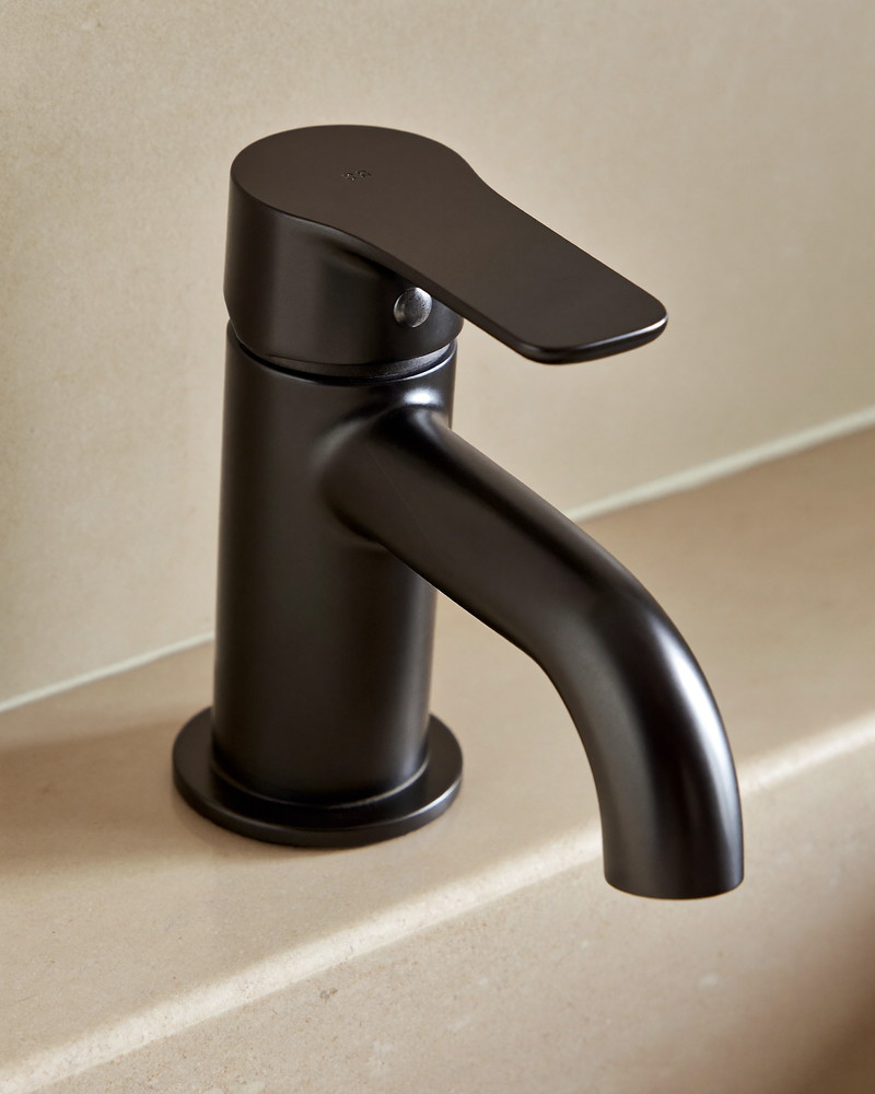 A matte black bathroom faucet with a smooth curved spout and a single smooth lever handle, completely plain unmarked metal with no engraving, mounted on