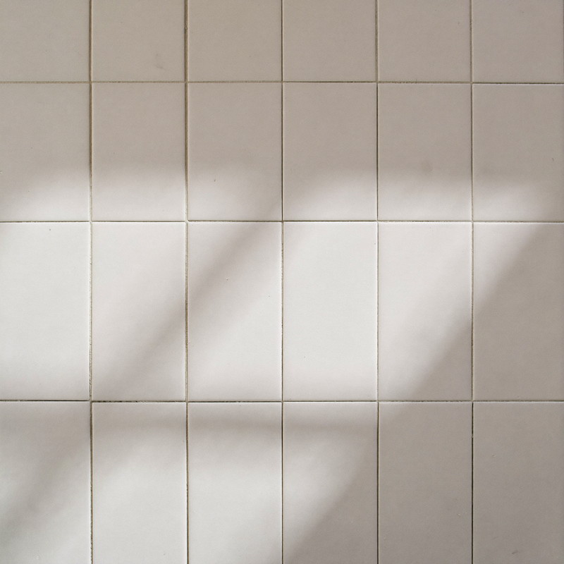 Macro photograph of classic white subway tile with soft gloss and thin pale-gray grout lines, plain field tile only, every course straight and flat, soft
