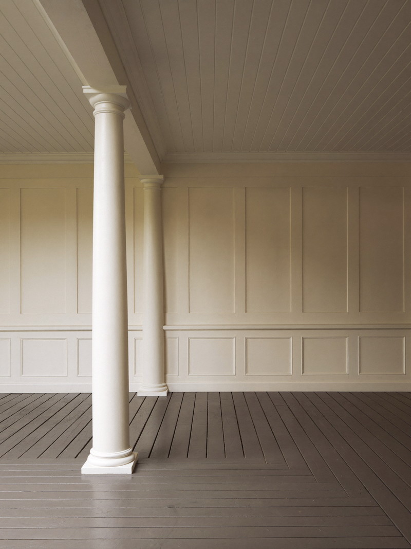 A restored farmer's porch on a well-kept Millis colonial: square white columns, warm gray painted fir floor, white beadboard ceiling, cream clapboard wall