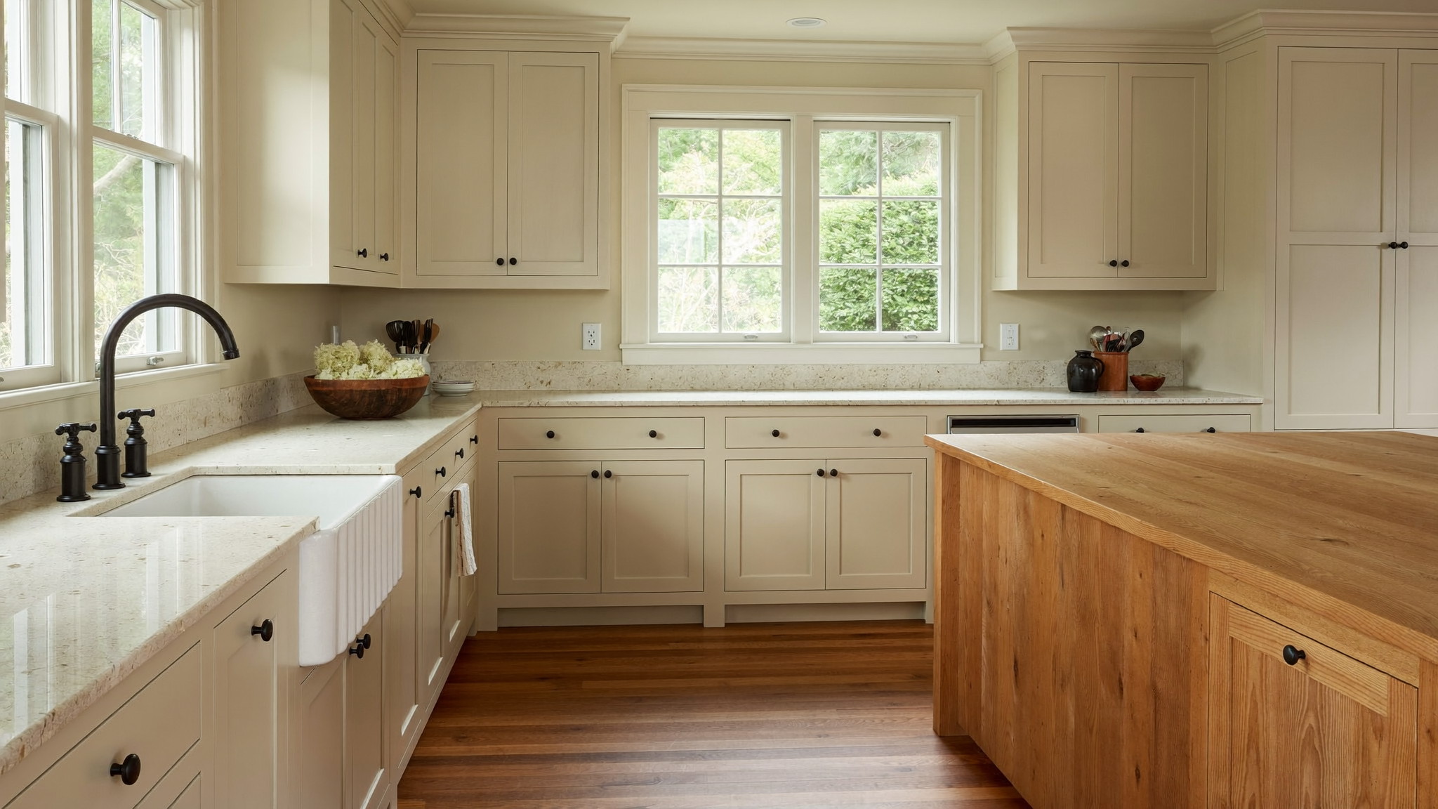 A renovated family kitchen inside a well-kept Millis Massachusetts colonial, photographed like a magazine feature: cream painted shaker cabinetry, creamy