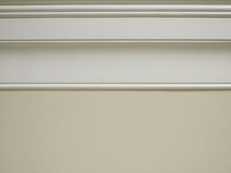 A razor-sharp paint line where a soft cream wall meets bright white crown molding, the edge perfectly straight and clean, smooth fresh paint on both