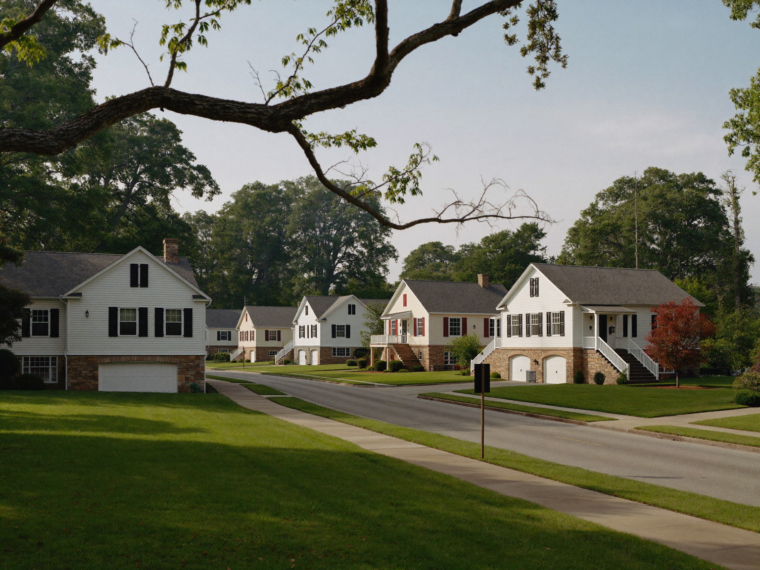 A quiet Millis Massachusetts road of well-kept freshly painted family homes: modest two-story white and cream colonials and capes with black and barn-red
