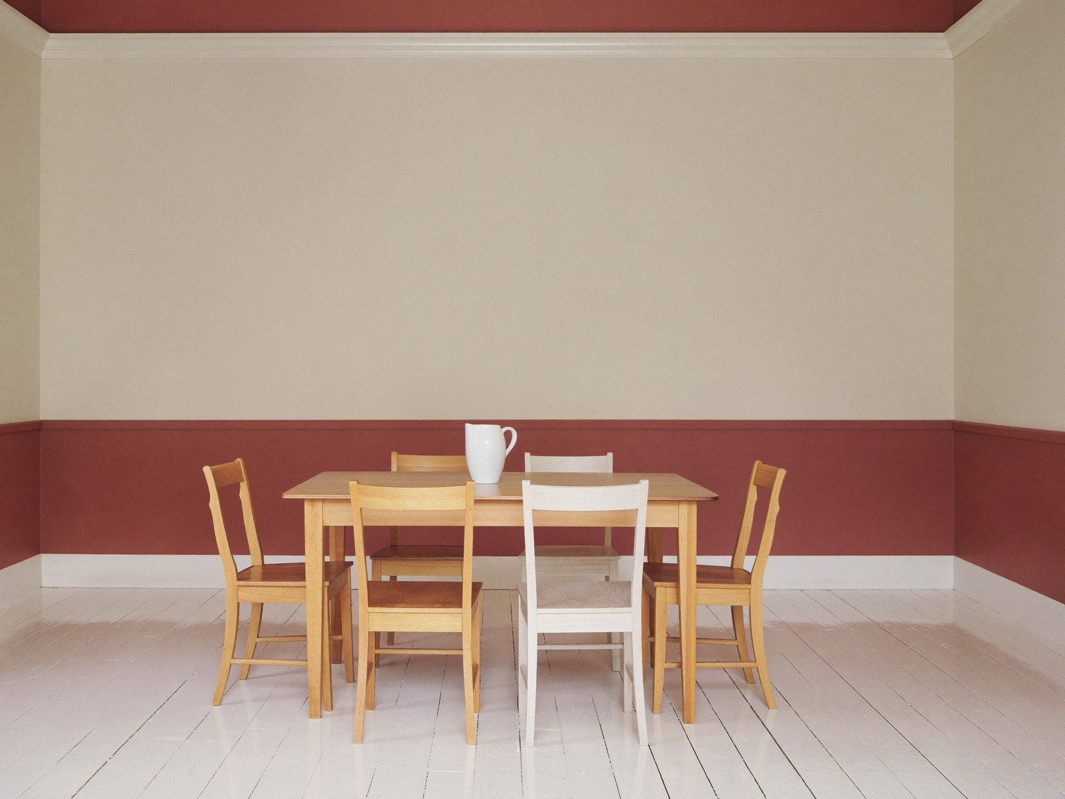 A repainted dining room in a well-kept Millis colonial: soft cream walls above a chair rail, muted barn-red below, glossy white trim and crown molding,