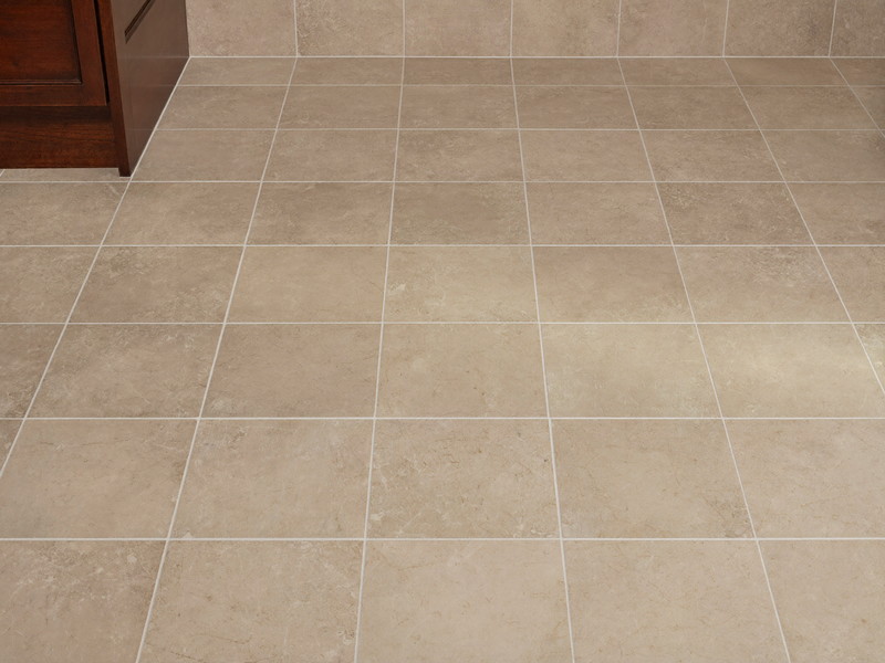 Soft quartzite-look large-format floor tile in a renovated suburban bathroom, plain field tile only, every tile flat and even, foot of a cherry wood
